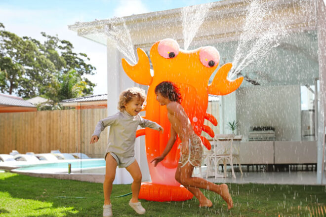 deux enfants jouant avec l'arroseur géant gonflable SUNNYLiFE Sonny la créature marine