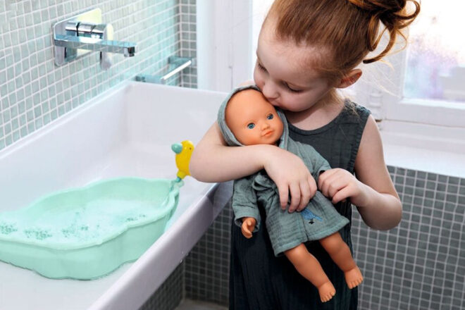 Un jeune enfant tient et embrasse sa Djeco Baby Doll dans la salle de bain
