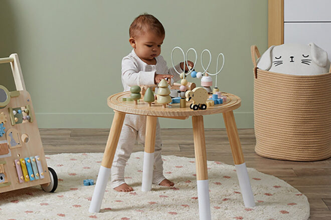 Table d'activités simulée montrant un tout-petit debout pour utiliser l'équipement de jeu situé sur le dessus dans des couleurs douces et apaisantes