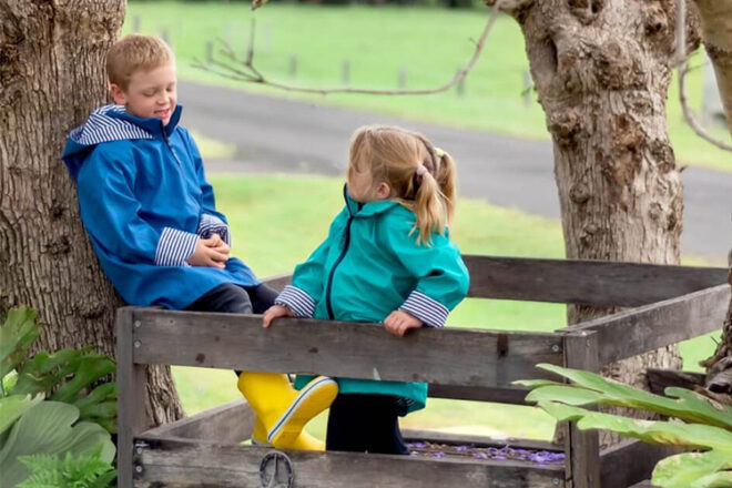 Deux enfants dans une cabane dans les arbres portant un imperméable pour enfants vert et bleu French Soda montrant l'utilisation et le style de la tenue