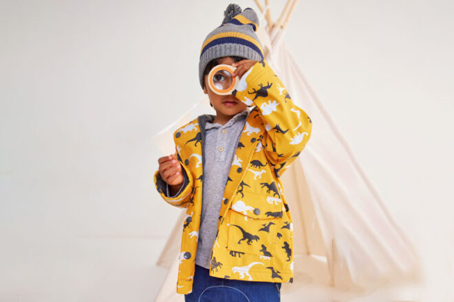 Enfant portant un imperméable Korango regardant à travers une loupe