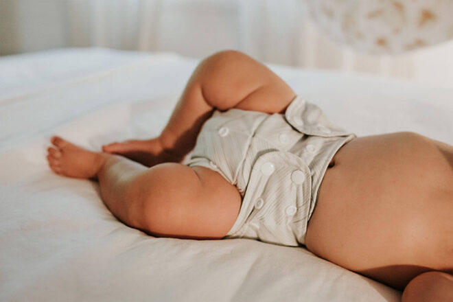 Bébé allongé sur son lit portant une couche en tissu Bare & Boho